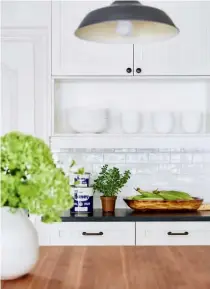  ??  ?? LEFT & LEFT, ABOVE In the kitchen, the white beadboard cabinetry offers a light and airy country look that’s grounded by darker elements, such as the leathered black granite perimeter countertop­s and slate-look floor tiles. The wide butcher...