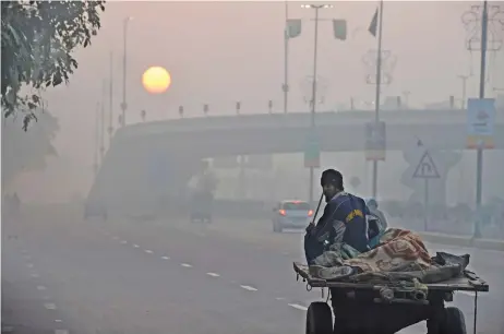  ?? (AFP) ?? A man rides his donkey cart amid heavy smog conditions in Lahore on December 6