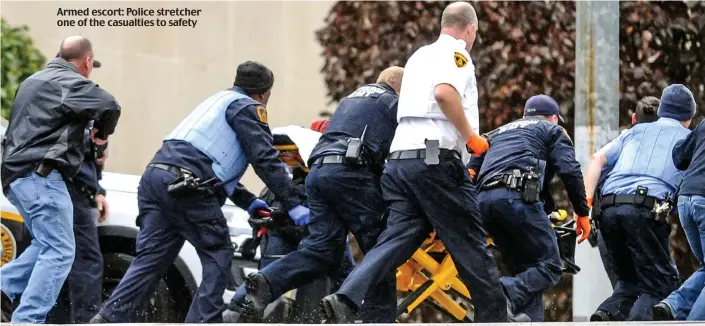  ??  ?? Armed escort: Police stretcher one of the casualties to safety