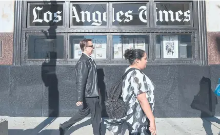  ?? AFP ?? Pedestrian­s walk past the Los Angeles Times office building on Wednesday.