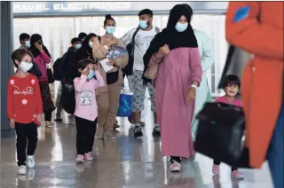  ?? Jose Luis Magana / Associated Press ?? Families evacuated from Kabul, Afghanista­n, walk through the terminal before boarding a bus after they arrived at Washington Dulles Internatio­nal Airport, in Chantilly, Va., on Wednesday.