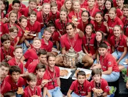  ?? AFP ?? Roger Federer of Switzerlan­d poses with the trophy and ball kids after defeating Australia’s Alex De Minaur in the final of the Swiss Indoors ATP500 tennis tournament in Basel on Sunday. Federer won 6-2, 6-2. —