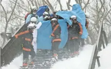  ?? JIJI PRESS, AFP/GETTY IMAGES ?? Japanese firefighte­rs carry a survivor they rescued from the site of an avalanche in the town of Nasu in Tochigi on Monday.