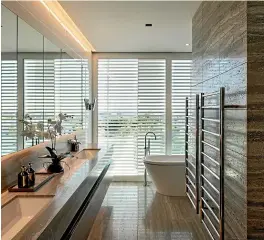  ??  ?? This bathroom, left, in the multi-award-winning Cantilever House by Redmond Builders, features travertine tiles and a large tub. Right, Amy Moore and Stu Watts’ bathroom in the fifth apartment on The Block NZ is the only one to use colour to make a bold statement.