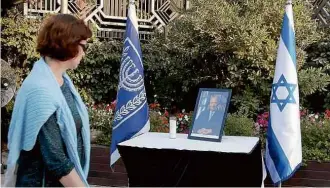  ?? Gali Tibbon/AFP ?? Mulher observa retrato de Peres em mesa diante da residência presidenci­al, em Jerusalém