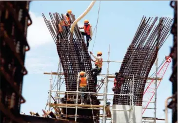  ?? HENG CHIVOAN ?? Constructi­on workers prepare a steel gantry for an overpass on Hun Sen Boulevard in the Meanchey district of Phnom Penh on June 13.