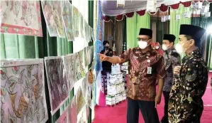  ?? GALIH WICAKSONO/JAWA POS ?? KREASI: Kepala Disparbud Gresik Sutaji Rudi (kiri), Kepala SD Irada Muh. Shobirin (tengah), dan Plt Kepala Dispendik Hariyanto melihat ratusan batik karya siswa SD Irada saat peringatan Hari Batik Nasional Sabtu (2/10).