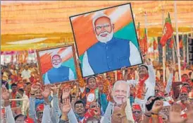  ?? AP ?? BJP supporters hold portraits of Prime Minister Narendra Modi during a public meeting, in Mehsana.