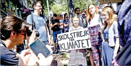  ??  ?? Swedish climate activist Greta Thunberg (centre) poses with a placard reading ‘School strike for the climate’ during a demonstrat­ion in Lausanne, Switzerlan­d, on August 9.