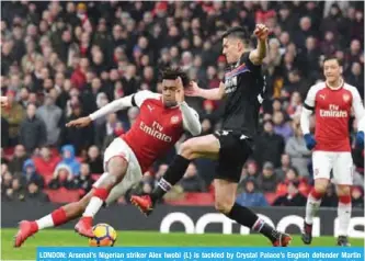  ?? — AFP ?? LONDON: Arsenal’s Nigerian striker Alex Iwobi (L) is tackled by Crystal Palace’s English defender Martin Kelly during the English Premier League football match between Arsenal and Crystal Palace at the Emirates Stadium in London yesterday.