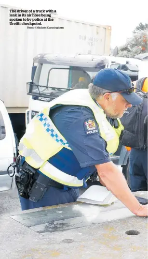  ?? Photo / Michael Cunningham ?? The driver of a truck with a leak in its air hose being spoken to by police at the Uretiti checkpoint.