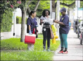  ?? JOE RAEDLE / GETTY IMAGES ?? Workers from the Florida Department of Health walk through a Miami Beach neighborho­od, asking residents if they would like to be tested for Zika on Wednesday.