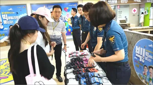  ?? — Photos for The Washington Post by Min Joo Kim ?? Police officers from Gyeonggi Nambu Provincial Police Agency hands out campaign stickers at a pool in suburban Seoul on July 23.