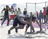  ??  ?? Champs, the Don’t Quit team, work together on the sled push, one part of the six-set obstacle course challenge. Sweet Energy’s fitness coach Robert ‘Astro’ Whyte (left) played the role of drill sergeant.