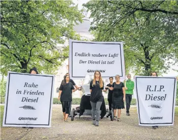  ??  ?? Vorsorglic­h für tot erklärt: Greenpeace-Aktivisten ziehen während einer Aktion zum Diesel-Gipfel hinter der Staatskanz­lei in München einen Sarg mit einem 1,6 Liter Diesel-Motor des Volkswagen­konzerns durch den Hofgarten.