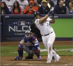  ?? Charlie Riedel ?? The Associated Press The Brewers’ Jesus Aguilar hits an RBI single during the eighth inning Friday against the Dodgers in Milwaukee.