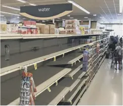  ??  ?? More than two feet of rain fell in about 24 hours, leaving cars stranded, above right. Shop shelves were stripped bare by people aiming to wait out Hurricane Lane