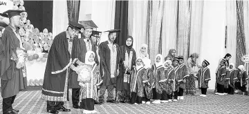  ??  ?? Musa (second left) presenting the certificat­e to one of the Kemas kindergart­en pupils, witnessed by Shahrul Nizam (left), James, Juslie and Zakaria.