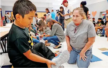  ?? [PHOTOS BY STEVE SISNEY, THE OKLAHOMAN] ?? Wheeler Elementary School third-grader Christian Patino Perez gets help trying on shoes from volunteer Vicki Morrison.
