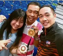  ??  ?? Winning
smiles: Wai Kin with parents Ng Ah Chiew and Peng Hoe holding up his two gold medals in Kuala Lumpur.