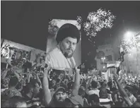  ?? AP PHOTO ?? Supporters of Shiite cleric Muqtada al-Sadr carry his image as they celebrate in Tahrir Square, Baghdad, Iraq on Monday.