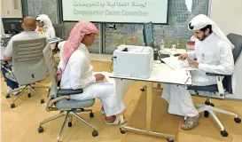  ?? (AFP) ?? This file photo shows staff at the office of the Compensati­on Claims Committee accepting papers from people affected by the diplomatic crisis, in Doha on July 27