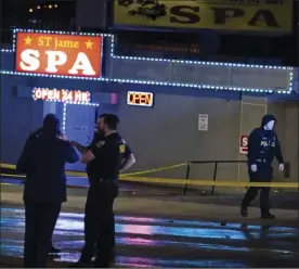  ?? AP file photo ?? Law enforcemen­t officials confer outside a massage business following a shooting in Atlanta, on March 16. Hours before the deadly Atlanta-area shootings spread fear and anger through Asian-American communitie­s nationwide, police say the attacker legally bought a handgun. They said that within hours, he had killed eight people, seven of them women and six of Asian descent, in a rampage targeting massage businesses.