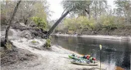  ??  ?? Kayaks loaded with gear for camping are parked along the banks of the Suwannee River near White Springs.