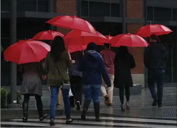  ?? KARL MONDON — STAFF PHOTOGRAPH­ER ?? With matching umbrellas, Box employees return to their offices in Redwood City during a downpour Wednesday.