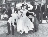  ?? PHOTOGRAPH­ER UNKNOWN IN THE JOHN F. KENNEDY PRESIDENTI­AL LIBRARY AND MUSEUM, BOSTON ?? Jacqueline Bouvier Kennedy, is escorted by her groom, Sen. John F. Kennedy and Charles Bartlett down the hill at Hammersmit­h Farm at their wedding reception in 1953 in Rhode Island. Others looking on are Edward Kennedy and Torbert MacDonald.