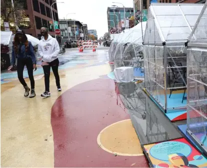  ?? NAM Y. HUH/ AP ?? People walk by outdoor plastic dining bubbles Oct. 18 on Fulton Market in Chicago. Colder temperatur­es are providing a new challenge for restaurant­s during the coronaviru­s pandemic.