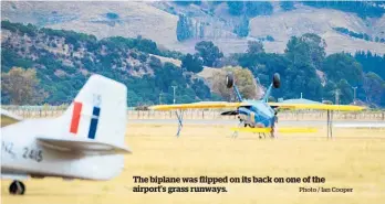  ?? Photo / Ian Cooper ?? The biplane was flipped on its back on one of the airport’s grass runways.