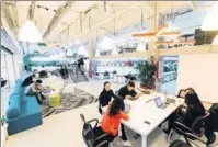  ?? PHOTOS PROVIDED TO CHINA DAILY ?? Tenants in the UrWork co-working space share a table in the public area, which is conducive to communicat­ion.