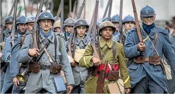  ?? AP ?? Men dressed in World War I uniforms march during a parade, part of a reconstruc­tion of the battle of Verdun in eastern France in August. With ceremonies marking the end of WWI looming, French President Emmanuel Macron wants them not to look like a military triumph.