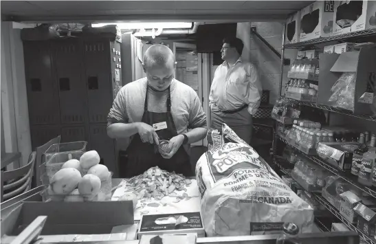  ?? TNS ?? Stephen Wittstadt peels potatoes at Sam’s Caterbury Cafe. Stephen and other disabled young adults on the autism spectrum are trained to do different jobs at the cafe. Michael Myers, right, is the owner. He founded the cafe as a place to employee his...
