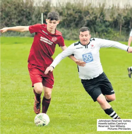  ??  ?? Johnstown Reserves’ Ashley Howells battles Caerbryn Reserves’ Sion Williams.Pictures: Phil Davies