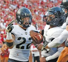  ?? AP PHOTO/SUE OGROCKI ?? Army quarterbac­k Kelvin Hopkins Jr., center, celebrates with teammates Calen Holt (22) and Camden Harrison, right, after scoring during the Black Knights' game at Oklahoma on Sept. 22. Army is this season's most aggressive FBS team on fourth down, having gone for it 48 percent of the time and converted 22 of those 25 attempts.