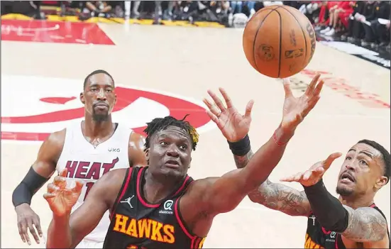  ?? ?? Atlanta Hawks Clint Capela, (front left), and John Collins, (right), reach for a rebound in front of Miami Heat center Bam Adebayo, (back left), in the first half of an NBA playoff basketball game in Atlanta. (AP)