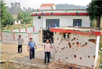  ?? — PTI ?? Villagers living near the border points out damage caused to the wall of a house after mortal shelling from Pakistan, at Jhanghar village near the Line of Control (LoC) at Nowshera sector in Jammu on Sunday.