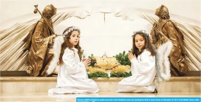  ??  ?? Kosovar children dressed as angels pray prior to the Christmas mass eve, marking the birth of Jesus Christ, on December 24, 2017 at the Mother Teresa cathedral in Pristina. — AFP