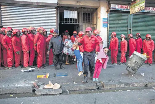  ?? Pictures: © James Oatway ?? ARMS AND THE MAN Red Ants officer Sikhumbuzo Dlamini carries two shocked children during an eviction in Bree Street, Johannesbu­rg, on June 23 last year.