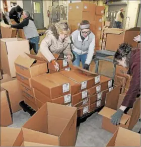  ??  ?? Sue Klaus and Jacquelyn Boyer fill boxes of food items to be delivered to area families during the Mercury’s annual Operation Holiday in Pottstown.