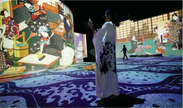  ?? Agence France-presse ?? ↑
A visitor takes pictures of projected images of Danny Rose Studio’s Dreamed Japan exhibit during a preview in Dubai on Monday.