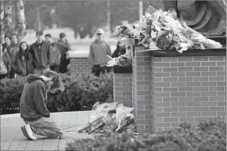  ?? PAUL SANCYA/AP PHOTO ?? A student kneels Tuesday where flowers are being left at the Spartan statue on the grounds of Michigan State University in East Lansing, Mich. A gunman killed several people and wounded others at the school. Police said early Tuesday that the shooter eventually killed himself.