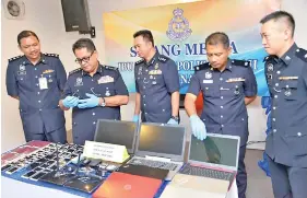  ??  ?? Omar inspecting one of the seized mobile phones during the raid at the Luyang call centre.