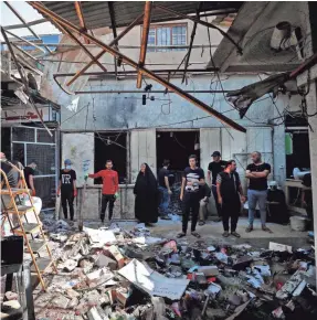  ?? AHMAD AL-RUBAYE/AFP VIA GETTY IMAGES ?? Iraqis inspect the site of an explosion in a market in the Shiite-majority Sadr City neighborho­od, east of Baghdad, on July 20. Iraqis mourned at least 36 people killed when a bomb ripped through the market in what Islamic State jihadists claimed was a suicide attack.