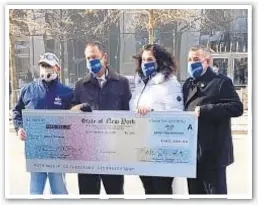  ??  ?? John Feal (left) and attorney Michael Barash (second to left) give $400,000 check Friday to Lisa Ferreyra and her husband John Ferreyra to help compensate $1 million payout from victims fund that John lost in a scam.