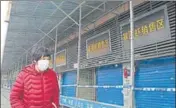  ?? AFP ?? GHOST TOWN: A woman walks past shuttered shops in Wuhan.