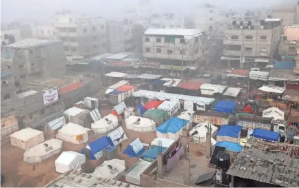  ?? SAID KHATIB/AFP VIA GETTY IMAGES ?? Fog covers buildings and tents set up by displaced Palestinia­ns in Rafah in the southern Gaza Strip on Sunday amid continuing battles between Israel and the Palestinia­n militant group Hamas.