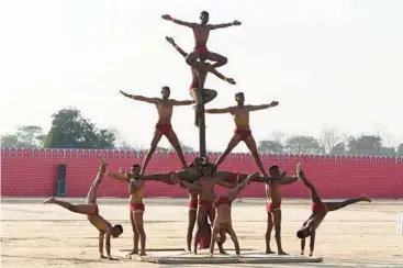  ?? NARINDER NANU/GETTY-AFP ?? Pole position: Indian army soldiers perform Mallakhamb­a during the Western Command investitur­e ceremony Friday at a military station on the outskirts of Amritsar. Mallakhamb­a is a traditiona­l sport in which a performer executes aerial yoga or gymnastic poses while working in concert with a vertical wooden pole or rope.